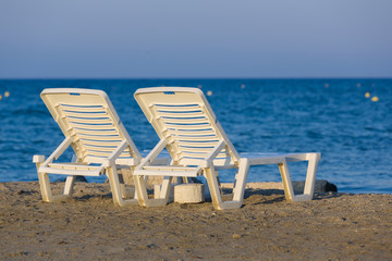 White, plastic sunbeds at golden hour on sandy beach of Zakynthos, Greece