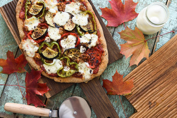 Fall comfort food. Homemade vegetarian pizza with eggplants, peppers and mozarella on oak boards with maple leaves