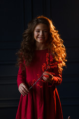 Young girl holding red berries branch. Portrait on black background