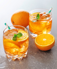 two glasses of orange cocktail on gray background