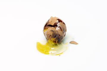 Cracked broken brown organic chicken egg, isolated on white background. Egg yolk and white spilling onto the surface.