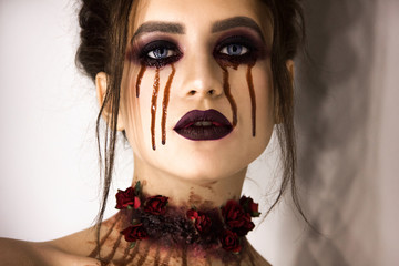 young stylish sexy brunette girl with halloween bloody makeup is standing and looking straight on...