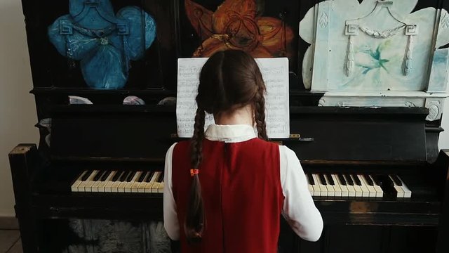 Playing piano music. Girl practicing on classical instrument.