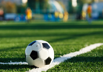 Fototapeta premium classical black and white football ball on the green grass of the field. Soccer game, training, hobby concept. with copy space 
