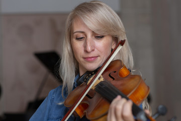 Young beautiful woman violin player looking at camera over instrument on her shoulder holding bow. © biggur
