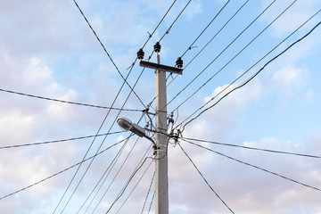 Line of electric poles with electrical and Internet cables against the sky with clouds. Street light. lighting and wiring