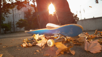 LOW ANGLE: Unknown young skater lands a trick in a pile of brown colored leaves.
