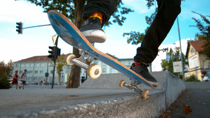 CLOSE UP Young male skateboarder tail grinds a concrete ledge in urban skatepark © helivideo