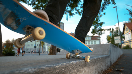 CLOSE UP: Unrecognizable skateboarder grinds a concrete ledge in the urban park.