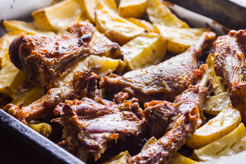 Baked meat with potatoes. Duck meat with golden crust on baking sheet. Cooked in oven dish on parchment. Golden sliced potatoes with chicken meat. Home kitchen