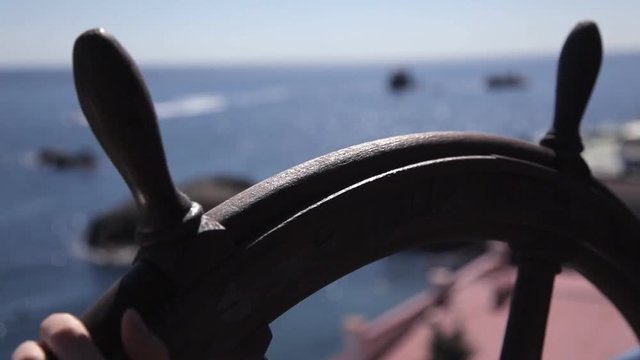 The girl rotates the helm of the ship with a sea view