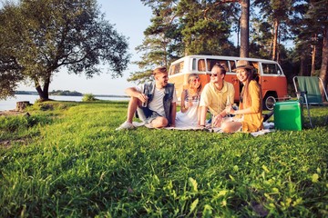 Hipster friends by camper van at festival on a summers day. © opolja
