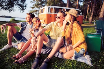 Hipster friends by camper van at festival on a summers day.