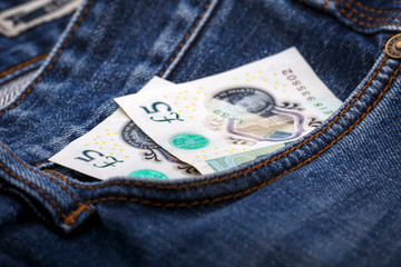 five british pound banknotes in pocket of blue jeans. Devon, United Kingdom, October 10, 2018