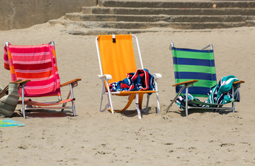 three colorful chairs on the sand, near the beach