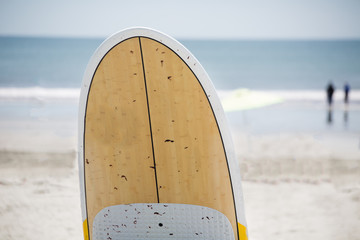 A fornt of a surfboard, blurred beach in background