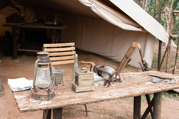 Obraz premium camping tent, old wooden table with explorer utensils