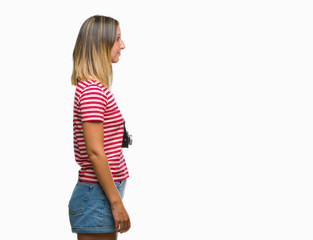 Young beautiful woman taking pictures using vintage photo camera over isolated background looking to side, relax profile pose with natural face with confident smile.