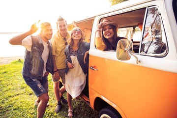 summer holidays, road trip, vacation, travel and people concept - smiling young hippie friends having fun over minivan car.