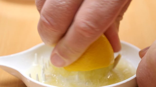 Male hand squeezing fresh lemon fruit using plastic juice squeezer. Making healthy citrus sour drink. Slow motion