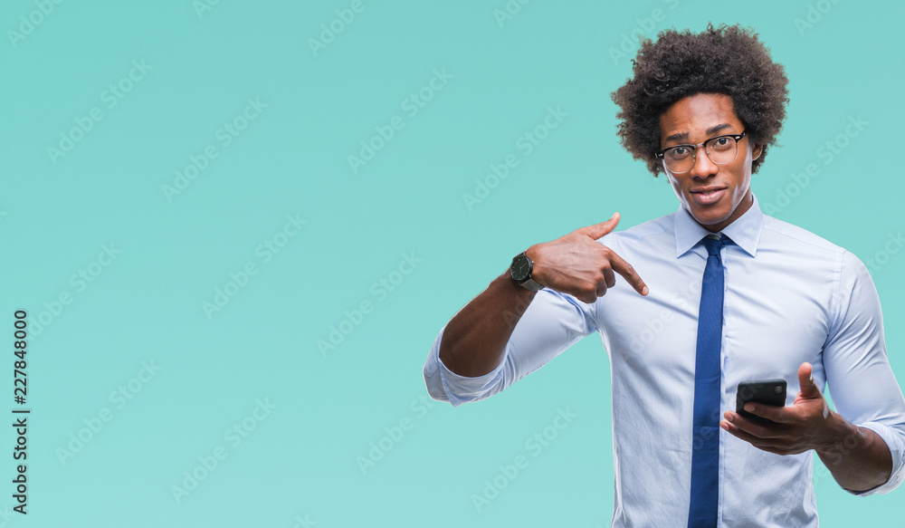 Wall mural Afro american business man texting using smartphone over isolated background with surprise face pointing finger to himself