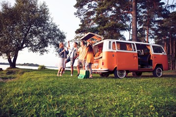 summer holidays, road trip, vacation, travel and people concept - smiling young hippie friends having fun over minivan car.