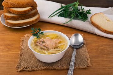Soup with noodles and chicken, fresh parsley and green onions, pieces of white wheat bread.