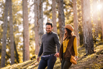 Beautiful smiling love couple walking in colorful autumn forest park