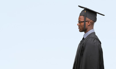 Young graduated african american man over isolated background looking to side, relax profile pose with natural face with confident smile.