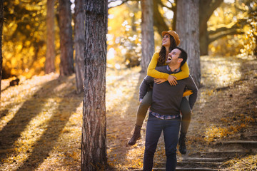 Beautiful smiling love couple walking in colorful autumn forest park