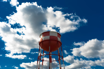 Colorful shot of a checkered water tower sitting in front of a bright blue sky with gorgeous clouds scattered behind it.