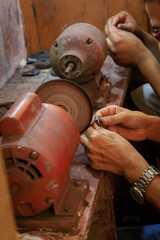 Jewelry smith polishes a lapis lazuli ring on a polishing machine in a backyard workshop in Puerto...