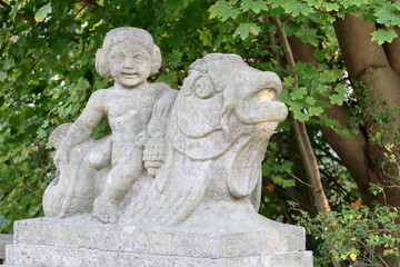 Fototapeta na wymiar Stone figure, weathered, child on fish, detail, bridge town Hamm in Germany