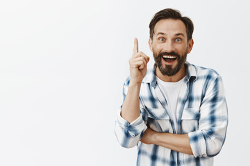 Hey eureka. Thrilled and excited friendly male model with beard and moustache raising index finger and smiling joyfully while being blessed with great idea, having plan and suggesting it to team