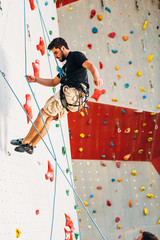 Muscular man descending down on a big wall