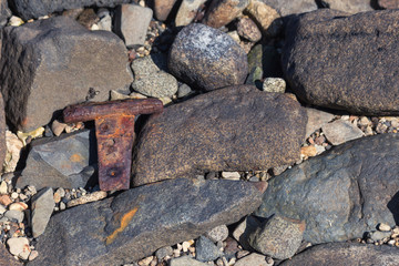 close up of rocks and stones on a beach  with a rusty hinge included