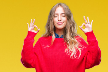 Beautiful young blonde woman wearing winter sweater over isolated background relax and smiling with eyes closed doing meditation gesture with fingers. Yoga concept.