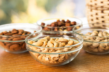 Assortment of mixed nuts and wicker basket on wood table background