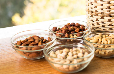 Assortment of mixed nuts and wicker basket on wood table background