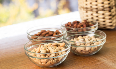 Assortment of mixed nuts and wicker basket on wood table background