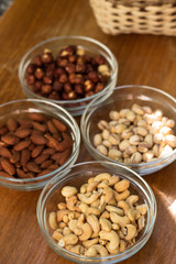 Assortment of mixed nuts and wicker basket on wood table background