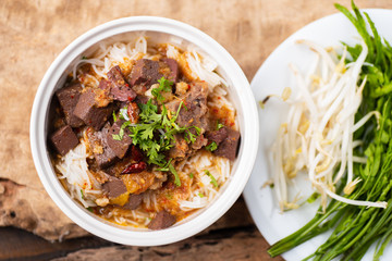 Northern Thai food (Kanom Jeen Nam Ngeaw) with vegetables on wooden background,spicy rice noodles soup
