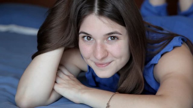 Young girl is lying on blue bed and posing on camera