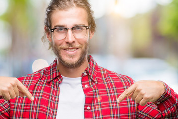 Young handsome man with long hair wearing glasses over isolated background looking confident with...