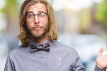 Young handsome man with long hair wearing bow tie over isolated background clueless and confused...