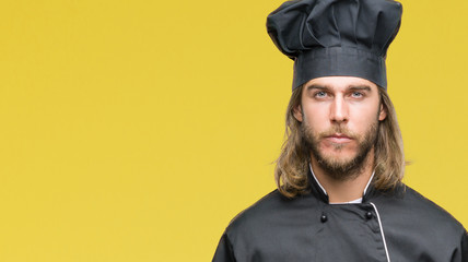 Young handsome cook man with long hair over isolated background with serious expression on face....