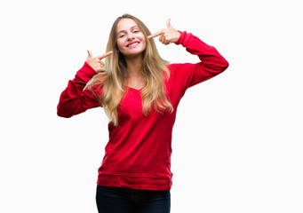 Obraz na płótnie Canvas Young beautiful blonde woman wearing red sweater over isolated background smiling confident showing and pointing with fingers teeth and mouth. Health concept.