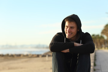 Teenage boy sitting on the beach looking away