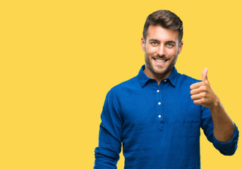 Young handsome man over isolated background doing happy thumbs up gesture with hand. Approving...