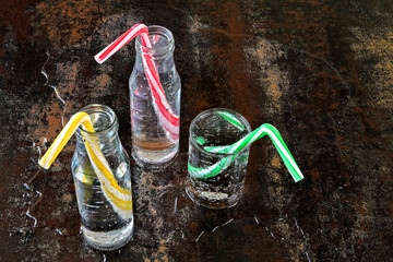 Mineral water in glass bottles and glass. Drinking bottled water with cocktail tubes on a stylish...